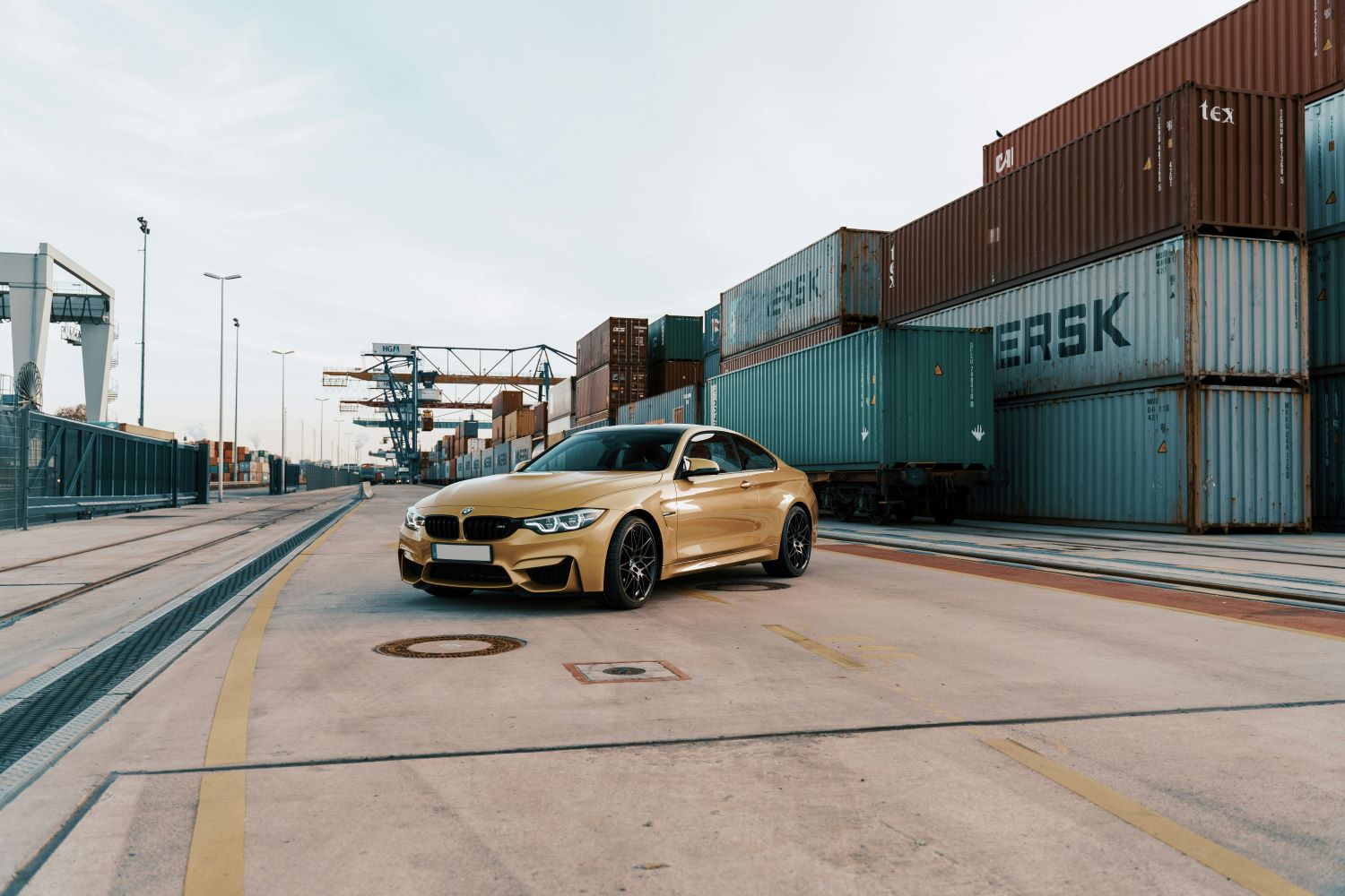 International car shipping from Australia - gold car in a shipyard surrounded by shipping containers