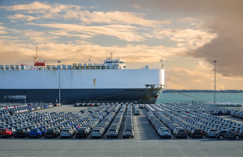 Roll on roll off shipping vessel on the water with hundreds of cars waiting to board.