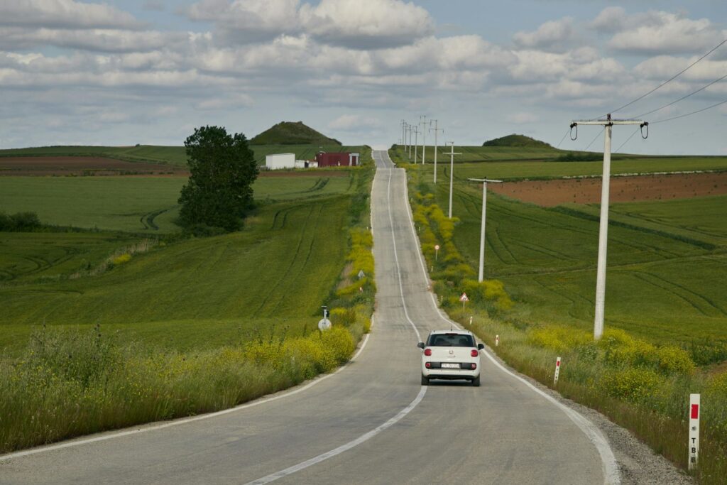 White car driving on overseas country road with a Carnet de Passage.
