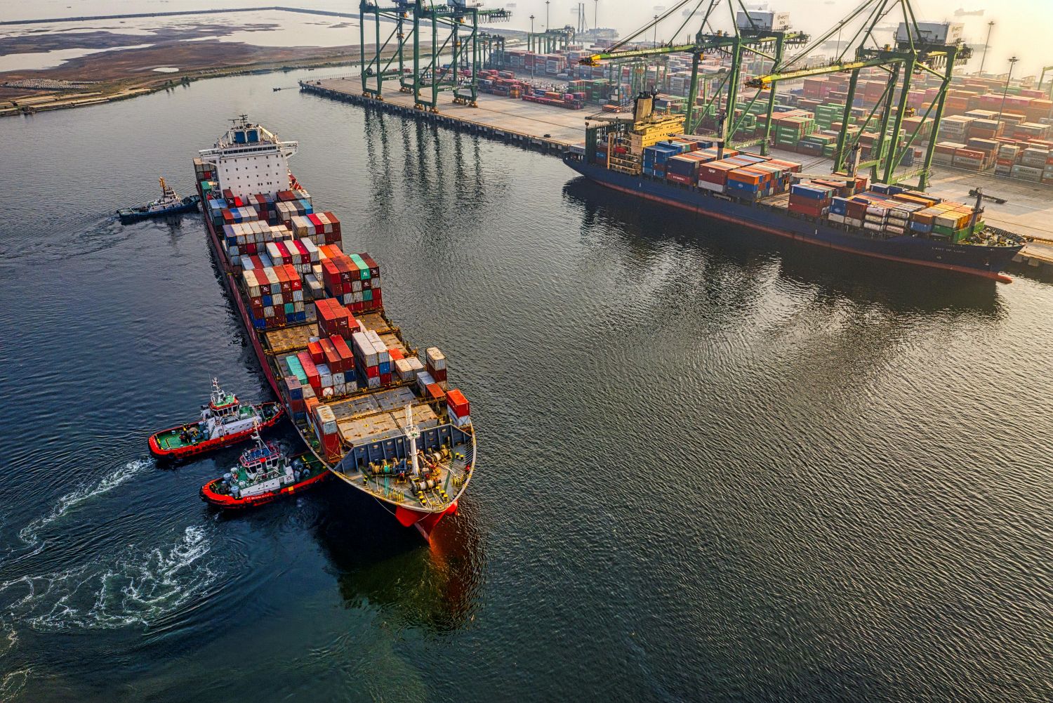 Large ship with sea cargo freight being loaded at a dock. Ocean shipping explained.