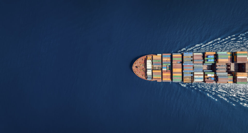 Aerial view of a container ship transporting goods across the ocean, representing international sea freight and global shipping routes.