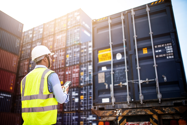 Foreman looking at cargo transport containers in a shipyard
