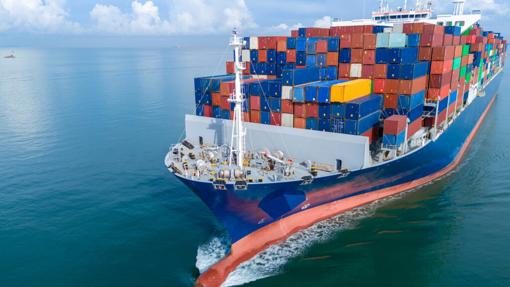 A cargo transport ship loaded with shipping containers, at sail in the sea.