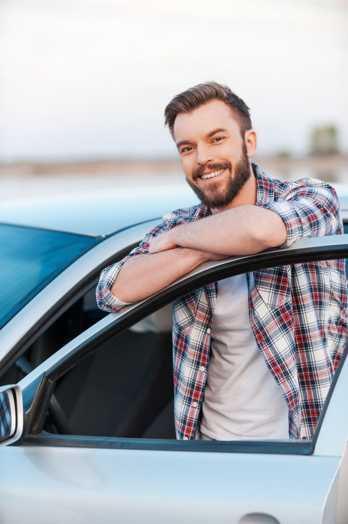 Smiling man leans against car door having imported japanese cars to australia