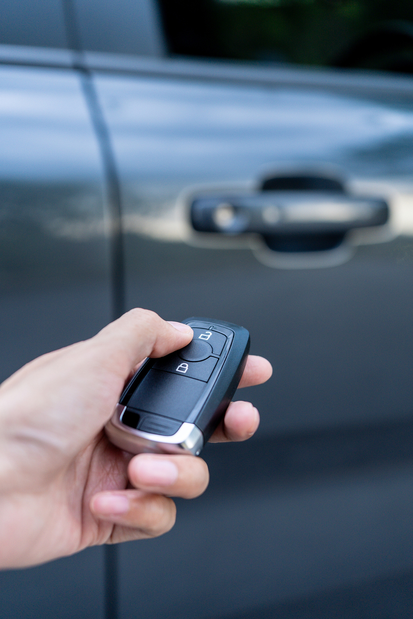 hold holding car keys locking car door with the japanese auto import in the background