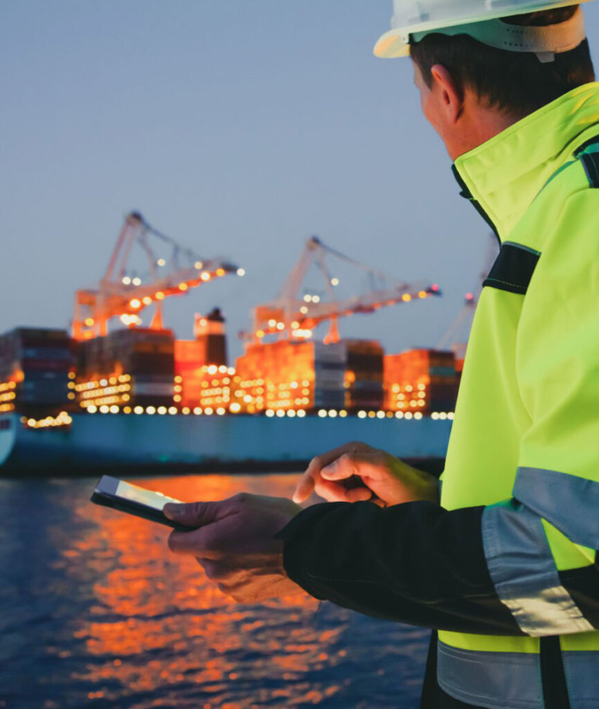 Freight forwarding company - Worker using a tablet and looking at a container ship