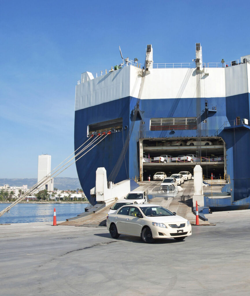 A huge ferry shipping vehicles overseas. A white car disembarking.